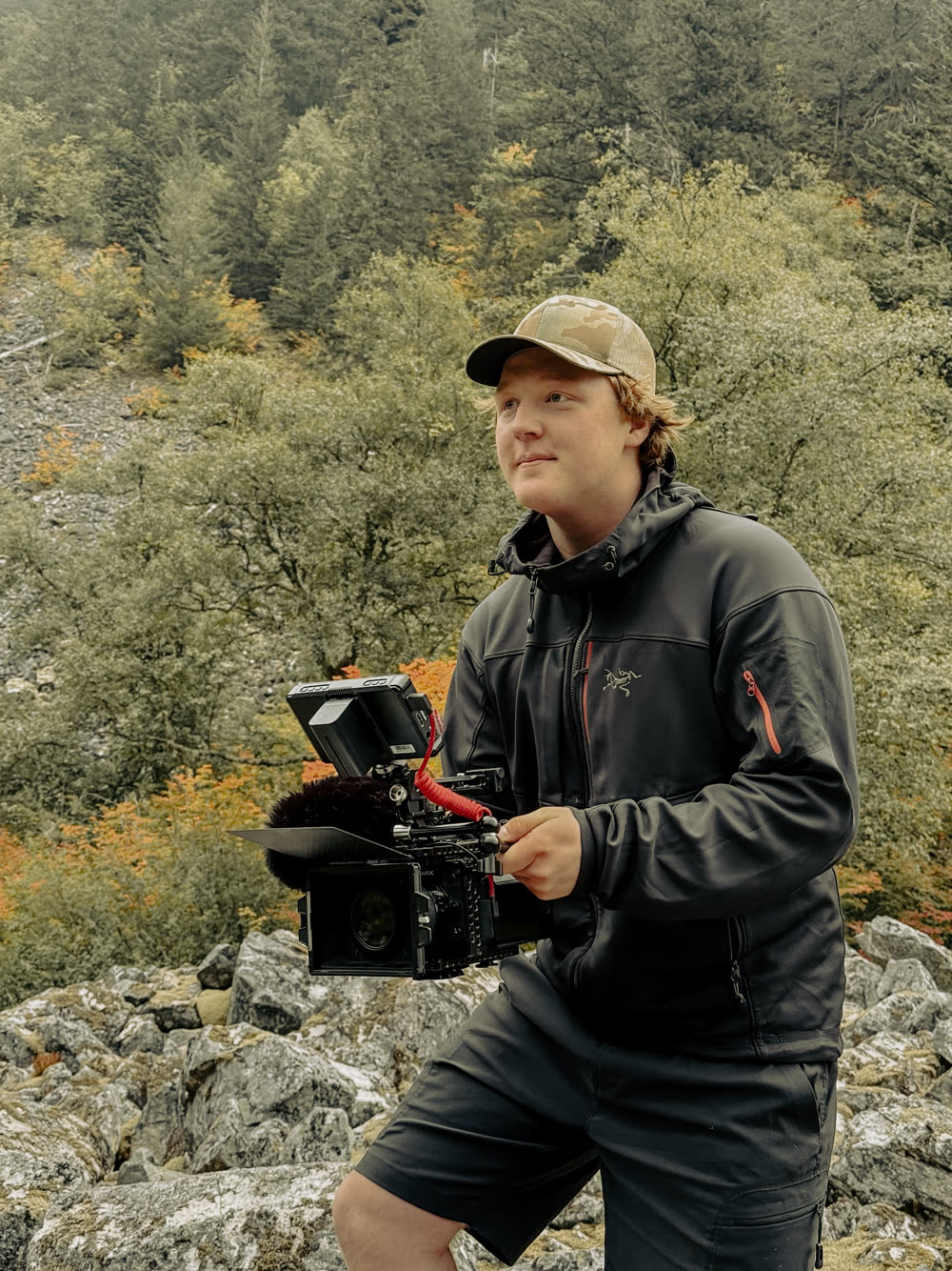 Lochlan Mayo holding a cinema camera in the mountains