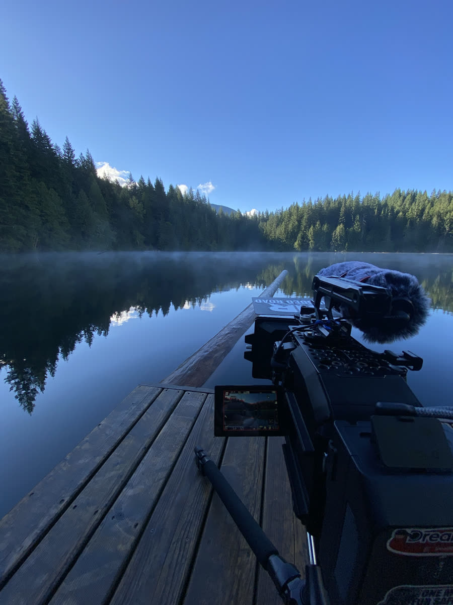 Cinema camera set up beside a misty mountain lake