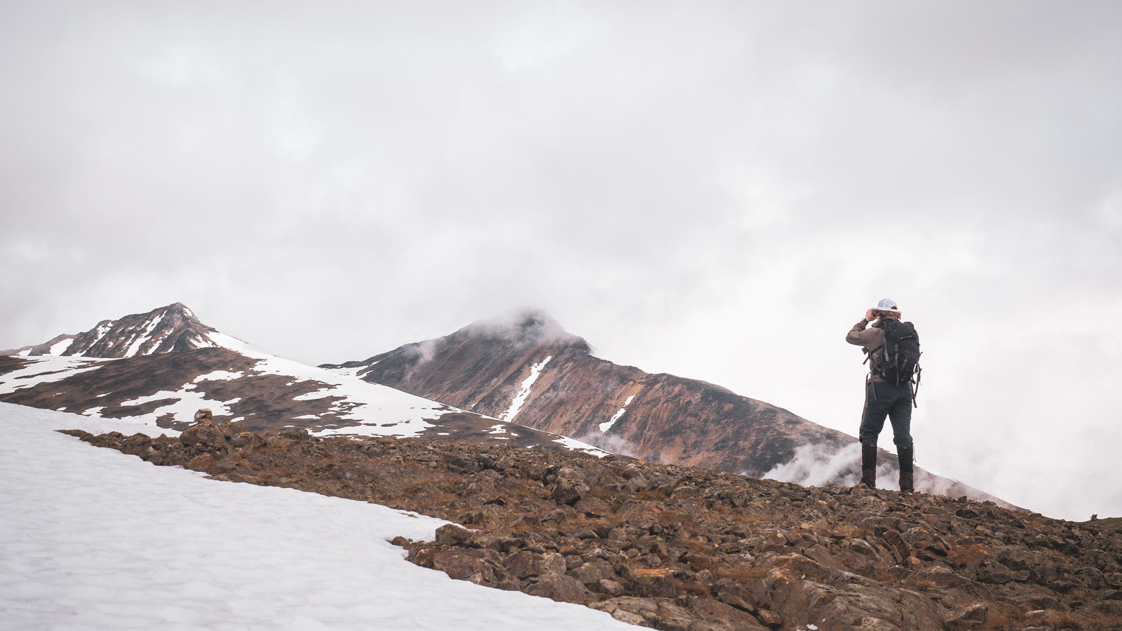 Filmmaker scouting a snowy mountain ridgeline